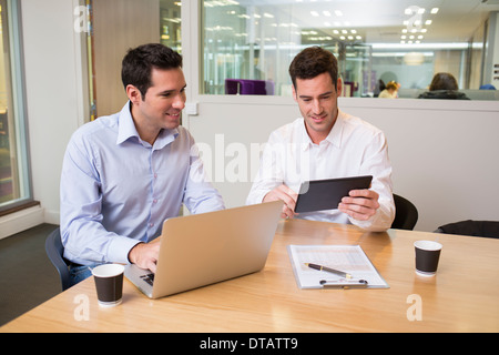 Zwei lässige Geschäftsleute arbeiten zusammen im Büro mit Laptop und Tablet pc Stockfoto