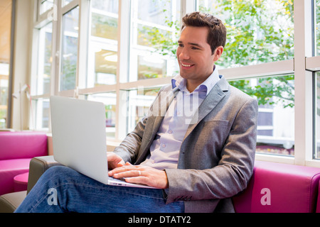 Glücklich lächelnd jungen Geschäftsmann arbeiten mit Laptop auf sofa Stockfoto