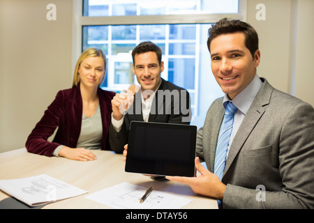 Lächelnd Geschäftsmann, ein neues Projekt auf Tablet an junges Paar, neue Eigentümer Stockfoto