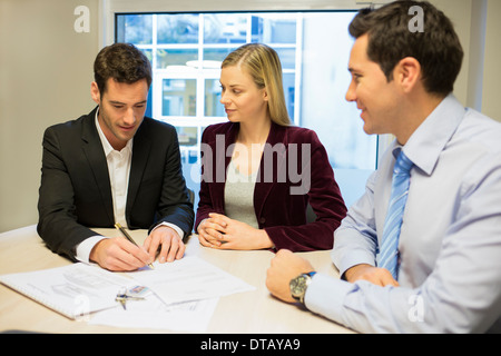 Junges Paar Vertragsunterzeichnung im Büro mit Immobilien, neue Eigentümer Stockfoto