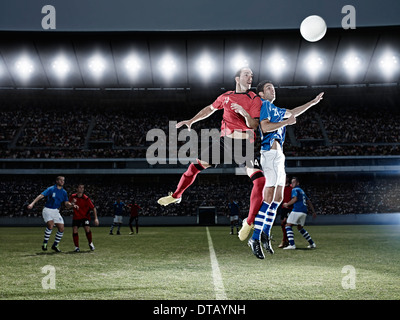 Fußball-Spieler für Kugel auf Feld springen Stockfoto