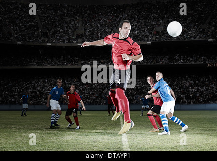 Fußballspieler springen auf Feld Stockfoto