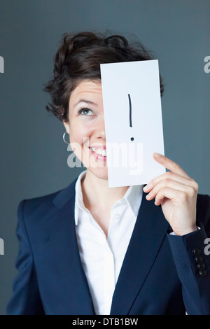 Mitte Erwachsene Frau mit Papier mit Ausrufezeichen und Lächeln auf den Lippen, Nahaufnahme Stockfoto