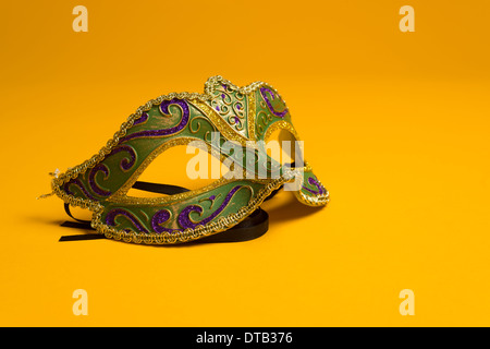 Grün, gold, lila Karneval Maske auf einem leuchtend gelben Hintergrund Stockfoto