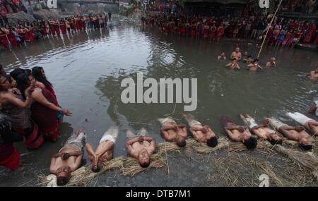 (140214)--KATHMANDU, 14. Februar 2014. (Xinhua)--nepalesische hinduistische Gläubigen beten, bevor nehmen Heilige am Fluss Hanumante während der letzte Tag des einmonatigen Madhav Narayan Festivals in Bhaktapur, Nepal taucht, 14. Februar 2014. Während der einmonatigen Festival nepalesische Hindu-Frauen ein Fasten und beten zu Göttin Swasthani für Langlebigkeit ihrer Ehemänner und Familie Wohlstand während unverheiratete Frauen beten zu treffen und einen guten Mann zu heiraten. (Xinhua/Sunil Sharma) Stockfoto