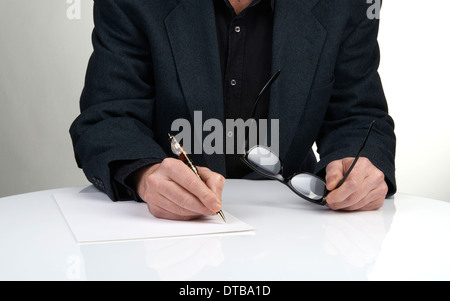 Nahaufnahme von den Händen eines Geschäftsmannes in einem Anzug Unterzeichnung oder Schreiben eines Dokuments auf ein weißes Blatt Papier mit einem Füllfederhalter Stockfoto