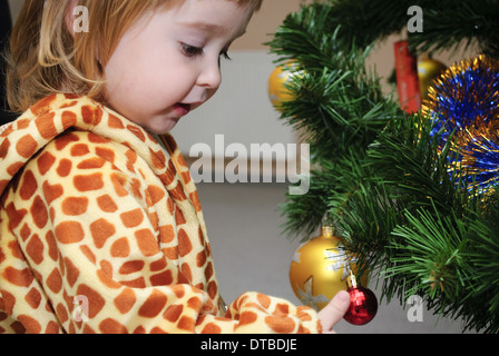 Kleines Mädchen in Tracht der Giraffe stehen in der Nähe der Neujahrsfeier und mit interessanten schauen. Stockfoto