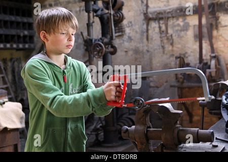 Pommern, Deutschland, arbeitete Young eine Eisenstange mit einer Säge Stockfoto