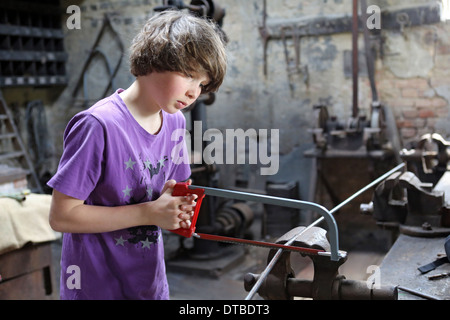 Pommern, Deutschland, arbeitete Young eine Eisenstange mit einer Säge Stockfoto