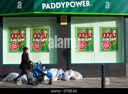 Eine Frau, die einen Kinderwagen schieben geht vorbei an einem Zweig der Paddy Power Buchmacher in Hackney, London, am 8. Januar 2014. Stockfoto