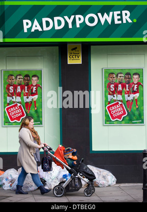 Eine Frau, die einen Kinderwagen schieben geht vorbei an einem Zweig der Paddy Power Buchmacher in Hackney, London, am 8. Januar 2014. Stockfoto