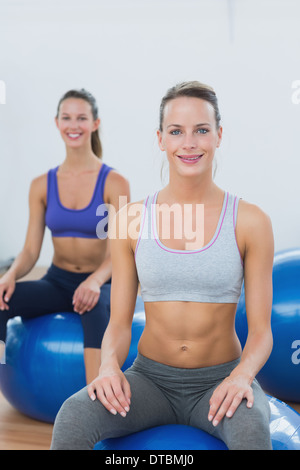 Sportliche Frauen sitzen auf Gymnastikbälle im Fitness-Studio Stockfoto