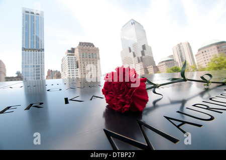 Eine einzelne rote Blume von Namen auf dem Denkmal-Brunnen an die 9/11 World Trade Center Tribute in New York City USA gelegt Stockfoto