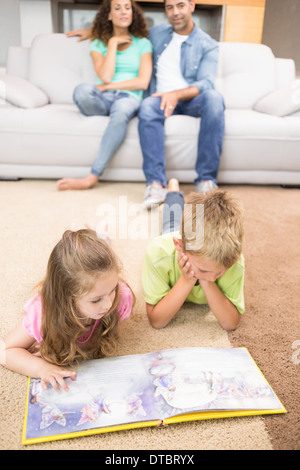 Glücklich Geschwister liegen auf dem Teppich ein Märchenbuch lesen Stockfoto