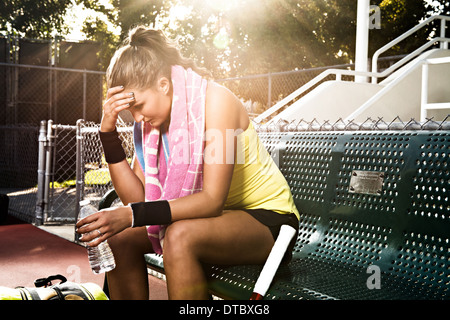 Tennisspielerin auf Bank mit Kopf in Händen Stockfoto