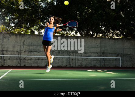 Weibliche Spieler schlagen Tennisball Stockfoto
