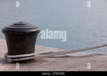 Liegeplatz-Post auf der Hafenseite mit einem Seil verbunden Stockfoto