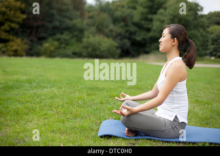 Junge Frau im Park üben Yoga Lotus-position Stockfoto