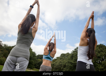 Drei junge Frauen praktizieren Yoga im park