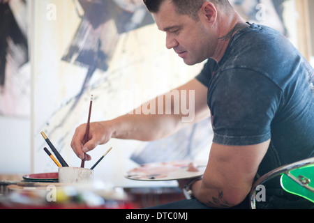 Ältere männliche Künstler arbeiten auf Leinwand im Atelier Stockfoto