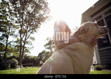 Junges Mädchen umarmt pet Labrador im Garten Stockfoto