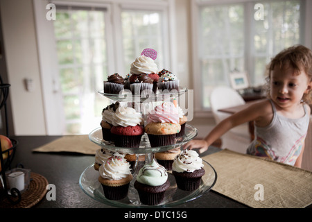 Weiblichen Kleinkind Blick auf Etagere voller Muffins Stockfoto