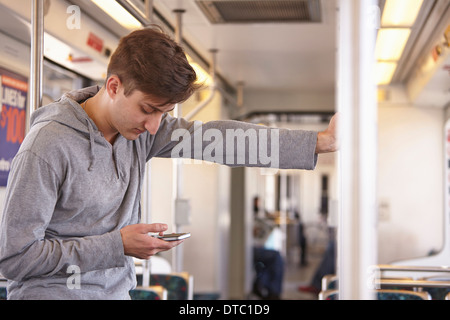 Mitte erwachsener Mann mit Handy in u-Bahn Stockfoto