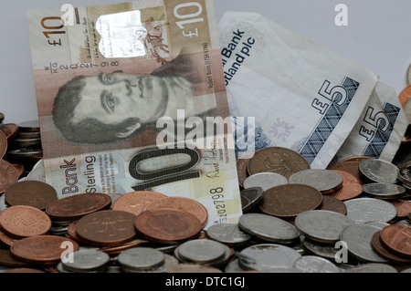 Verschiedene Münzen und Banknoten vor einem weißen Hintergrund. Währung in Großbritannien. Schottische Noten. Stockfoto