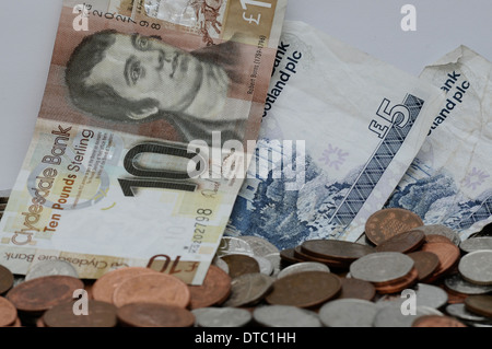 Verschiedene Münzen und Banknoten vor einem weißen Hintergrund. Währung in Großbritannien. Schottische Noten. Stockfoto