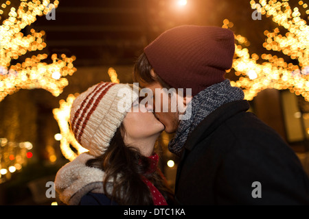 Junges Paar küssen auf der Straße zu Weihnachten Stockfoto