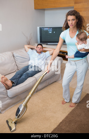 Junge Frau, die Reinigung des Hauses während des Tragens baby Stockfoto