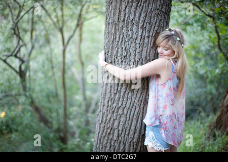 Teenager-Mädchen umarmt Baum im Wald Stockfoto