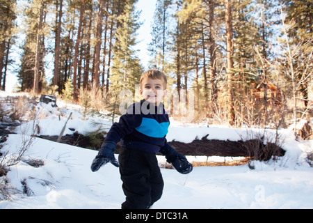 Männliche Kleinkind spielen im verschneiten Wald Stockfoto