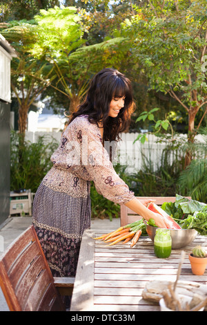 Junge Frau mit Gemüse auf Tisch Stockfoto