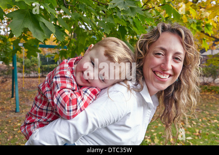 Porträt der Mutter mit jungen Sohn Piggy back im Garten Stockfoto