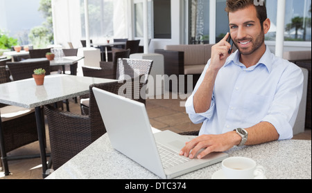 Fröhliche Geschäftsmann mit seinem Laptop telefonieren Stockfoto