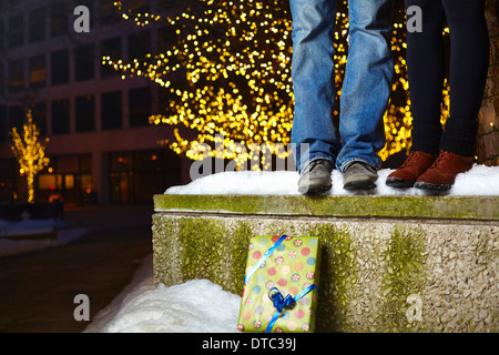 Die Beine des jungen Paares auf Schnee stehen bedeckt Wand in Stadt Stockfoto