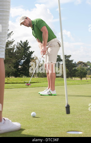 Junge männliche Golfer putting auf Golf grün Stockfoto