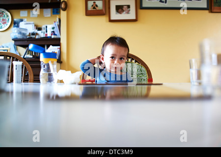 Baby Junge saß am Küchentisch Stockfoto