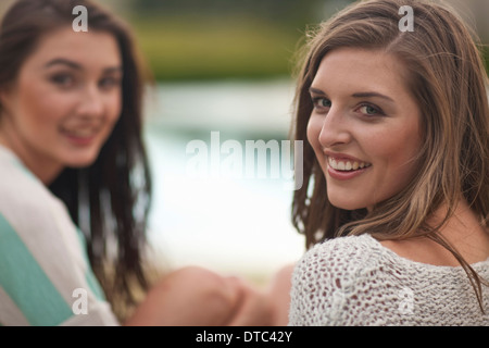 Zwei junge Frauen sitzen von riverside Stockfoto