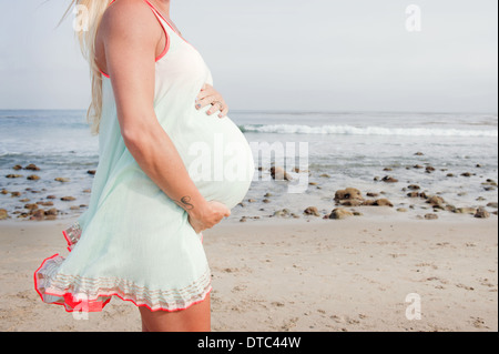Abgeschnitten Bild der schwangeren jungen Frau am Strand Stockfoto