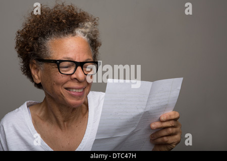Studioportrait glücklich senior Frau liest einen Brief Stockfoto