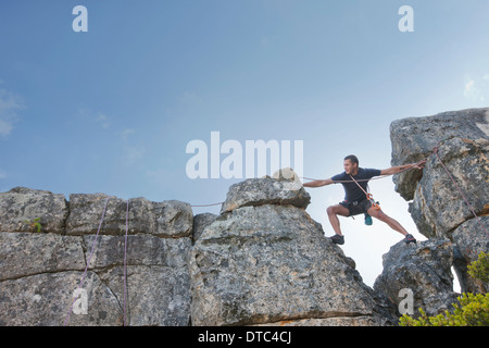 Junger Mann verstärkt und erreichte am Klettern Stockfoto