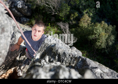 Junge männliche Kletterer beobachten und warten auf die Felswand Stockfoto