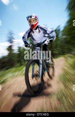 Weibliche Mountainbiker bergab zu beschleunigen Stockfoto