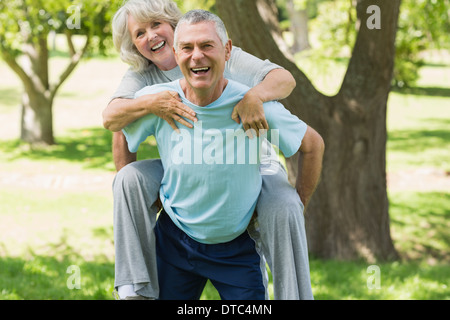 Fröhliche reifer Mann trägt Frau im park Stockfoto