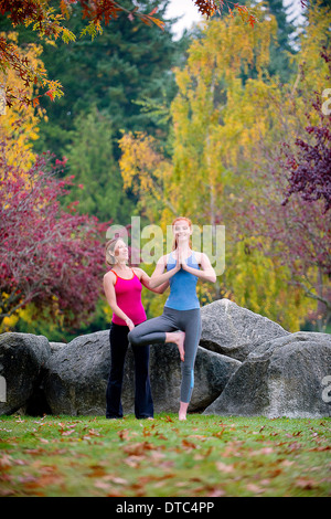 Yoga-Lehrer unterrichten junge Frau im Wald Stockfoto