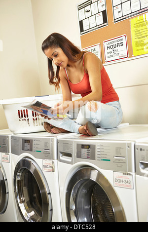 Junge Frau, die Wäsche im Waschsalon Stockfoto