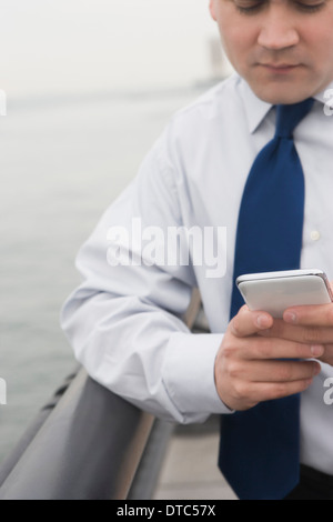 Geschäftsmann, stützte sich auf Schiene SMS Stockfoto