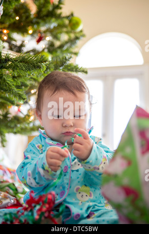 Babymädchen öffnen Weihnachten präsentiert ihr erstes Weihnachten Stockfoto
